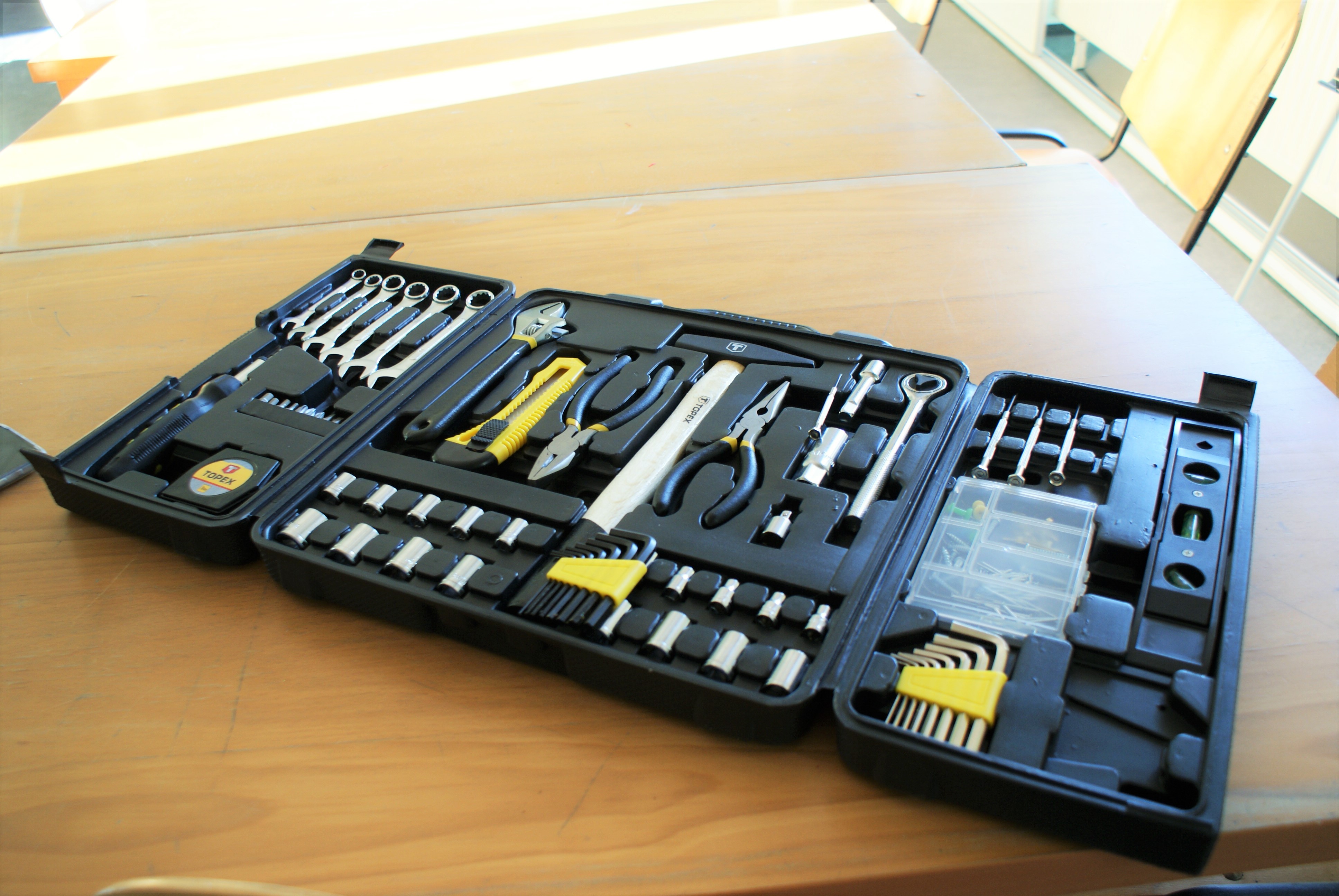 otwarte pudełko z narzędziami m.in. nożyk do taper, kombinerki, klucze, miarka, śrubokręt itp.