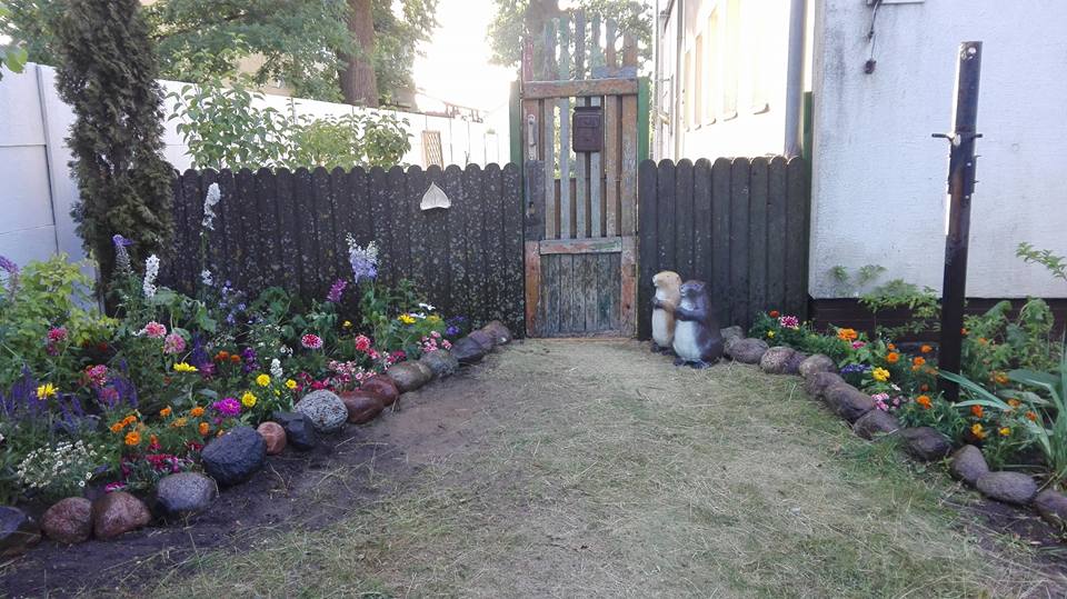 Ogród z kolorowym skalniakiem i figurkami bobrów.