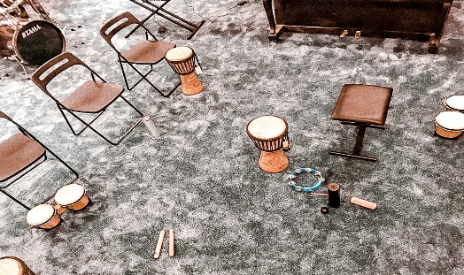 Sala z rozstawionymi krzesłami i instrumentami m.in. bębnami, ustawionymi na podłodze.