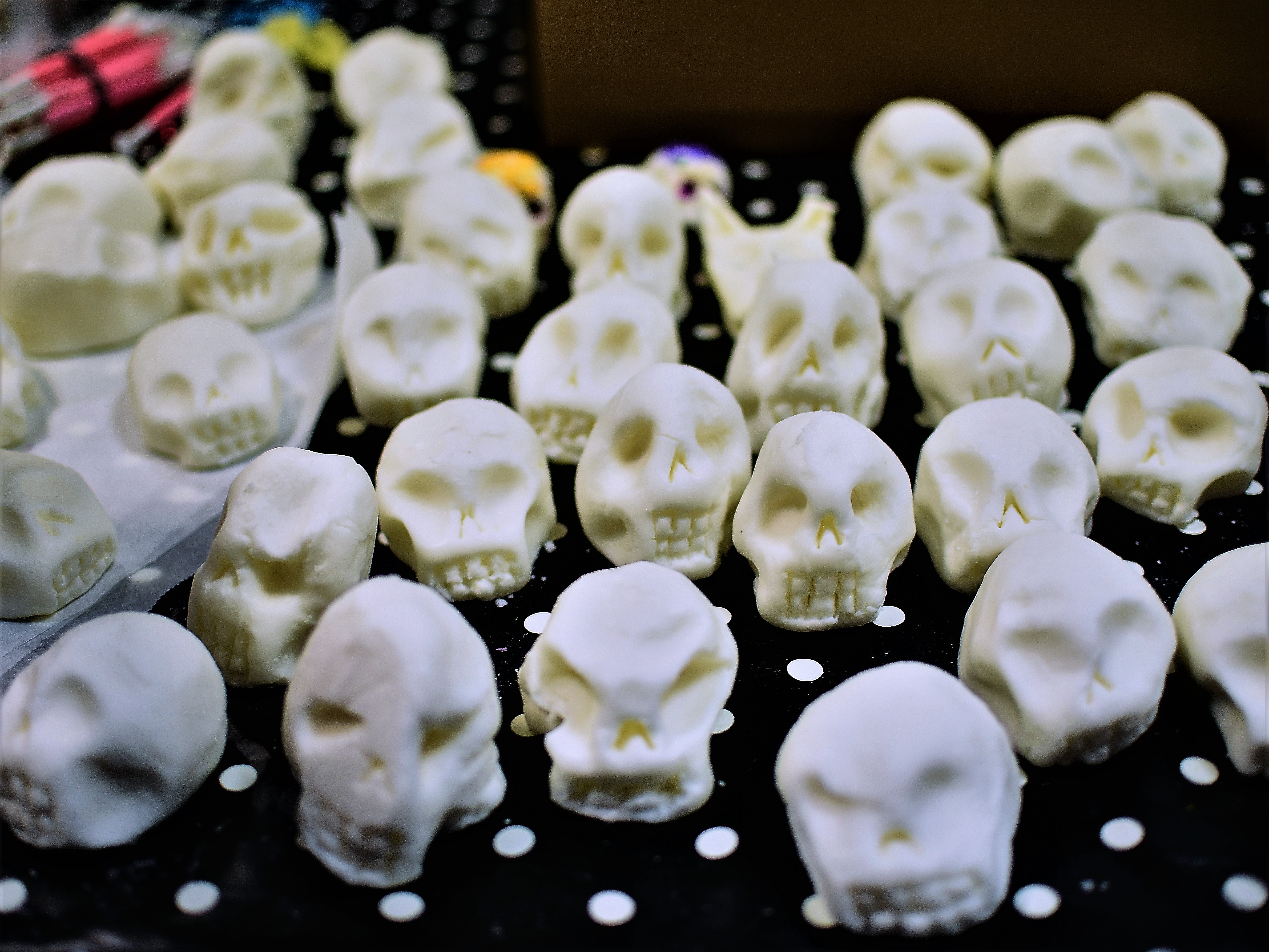 Zdjęcia z wystawy przedstawiające przedmioty w kształcie czaszek.