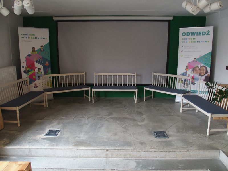 Zdjęcie przestrzeni z ławkami do siedzenia i ekranem do rzutnika.