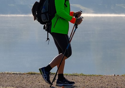 osoba idąca z kijkami nordic walking wzdłuż wody